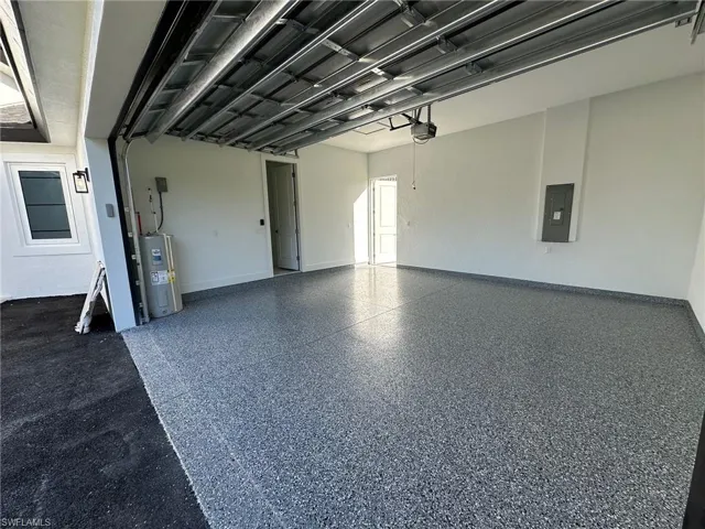 Garage featuring electric water heater and electric panel