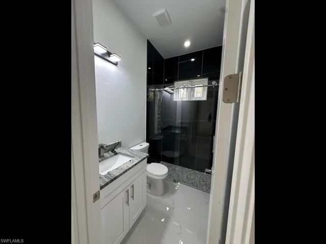 Full bath featuring vanity, a shower stall, and light marble finish floors