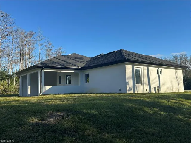 Rear view of house with stucco siding and a yard