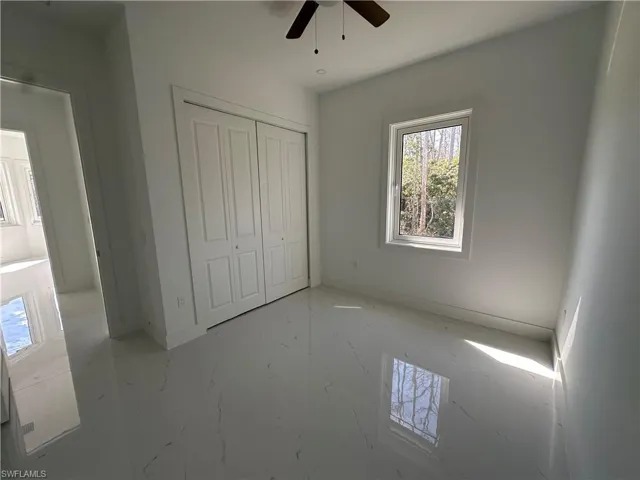 Unfurnished bedroom with light marble finish flooring, a closet, and ceiling fan