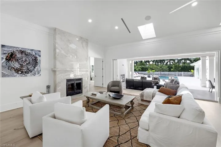 Living area featuring a fireplace, wood finished floors, recessed lighting, a skylight, and crown molding