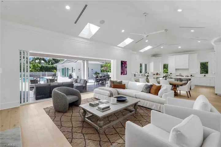 Living area featuring light wood-style floors, recessed lighting, ornamental molding, a ceiling fan, and high vaulted ceiling