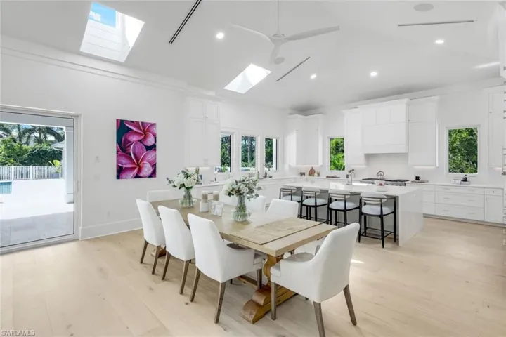 Dining room featuring light wood-type flooring, recessed lighting, a ceiling fan, a skylight, and vaulted ceiling