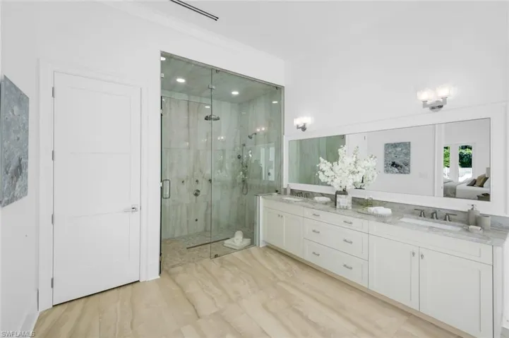 Full bathroom featuring double vanity, a shower stall, ensuite bathroom, and light wood-style floors