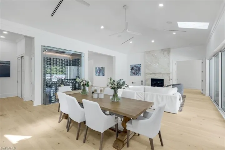Dining room with a fireplace, light wood-style floors, recessed lighting, a skylight, and a ceiling fan
