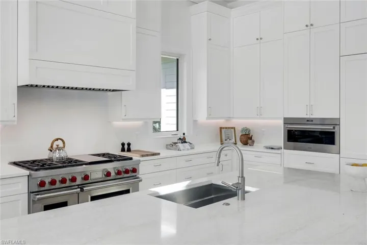 Kitchen featuring stainless steel appliances, white cabinetry, and light stone countertops
