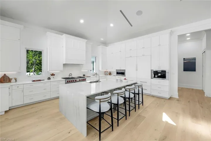 Kitchen featuring a kitchen breakfast bar, light stone countertops, light wood finished floors, recessed lighting, and a spacious island