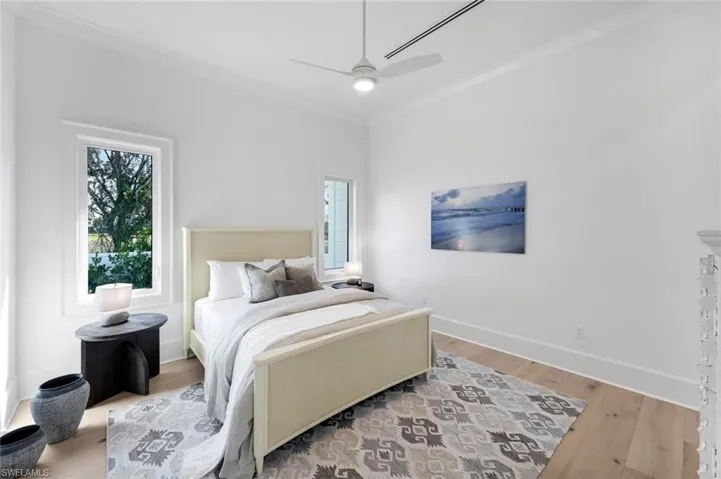 Bedroom with crown molding, light wood-type flooring, and a ceiling fan