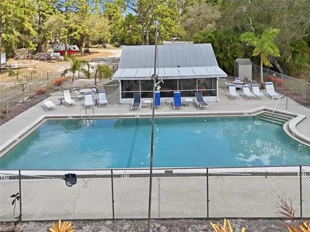 Community pool with a patio and view of wooded area