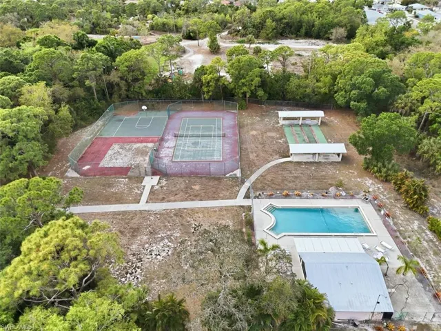 Drone / aerial view of a tree filled landscape and a pool