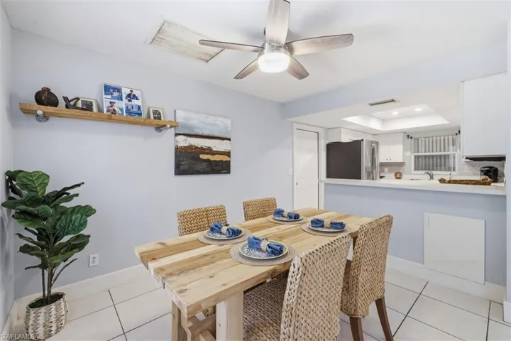 Dining space featuring light tile patterned floors, a tray ceiling, and ceiling fan