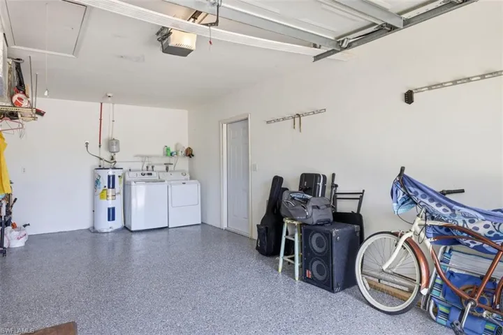 Garage featuring independent washer and dryer, electric water heater, and a garage door opener