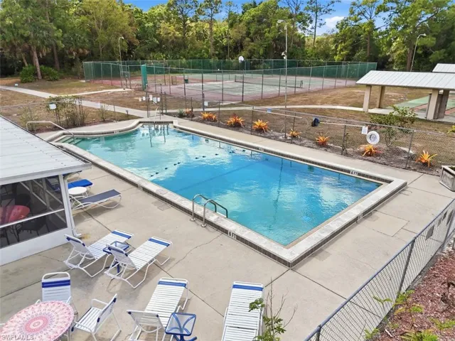 Community pool with a patio area and view of scattered trees