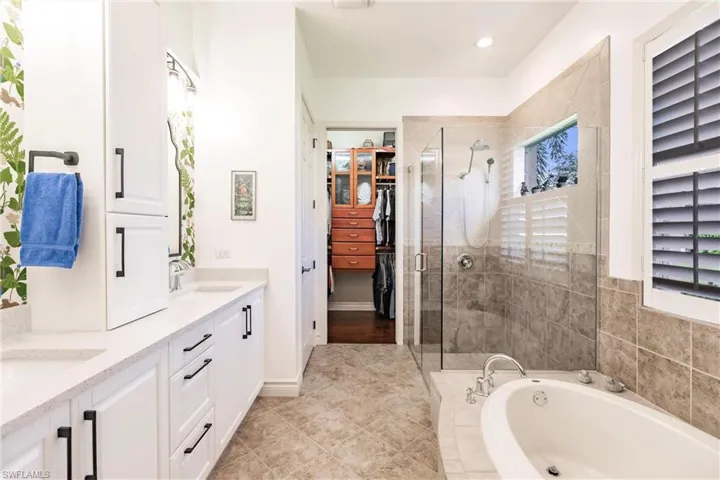 Full bathroom featuring double vanity, a garden tub, a spacious closet, a stall shower, and recessed lighting