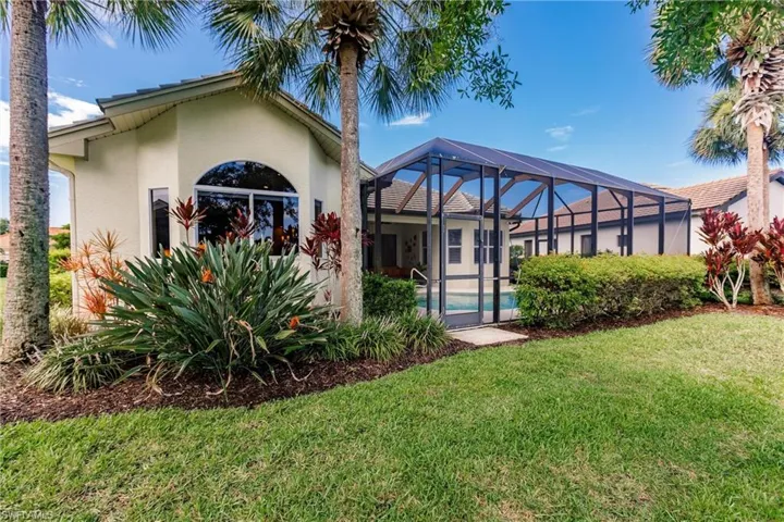 Back of property with a sunroom, stucco siding, a lanai, a yard, and an outdoor pool