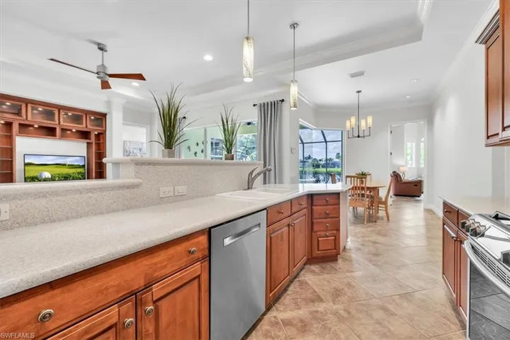 Kitchen featuring wood cabinetry, light-toned countertops, and a stainless steel dishwasher