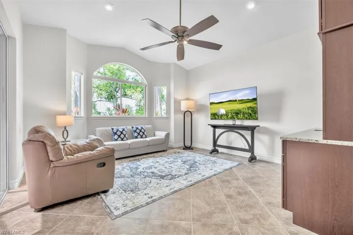 Living area featuring vaulted ceilings, recessed lighting, a ceiling fan, and large arched windows
