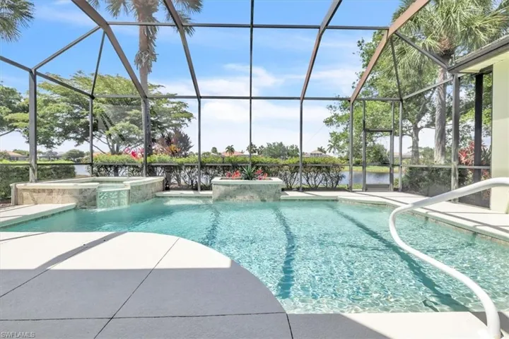 Screened-in outdoor pool featuring an integrated spa with waterfall, a sun shelf, and a curved entry handrail