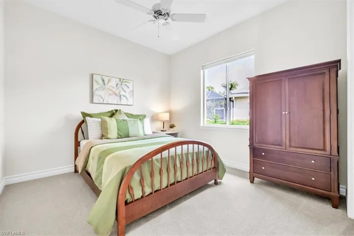 Spacious room featuring neutral carpeting, a large window, a ceiling fan, and crown molding