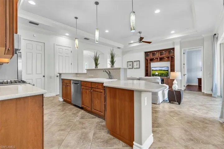 Open-concept kitchen and living area featuring a large center island with integrated sink, stainless steel dishwasher, and pendant lighting