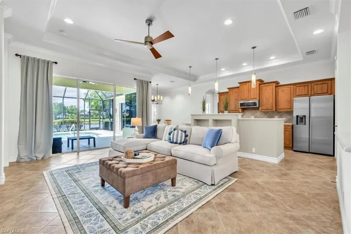 Open concept living area featuring tile flooring, tray ceilings with recessed lighting, and a modern ceiling fan