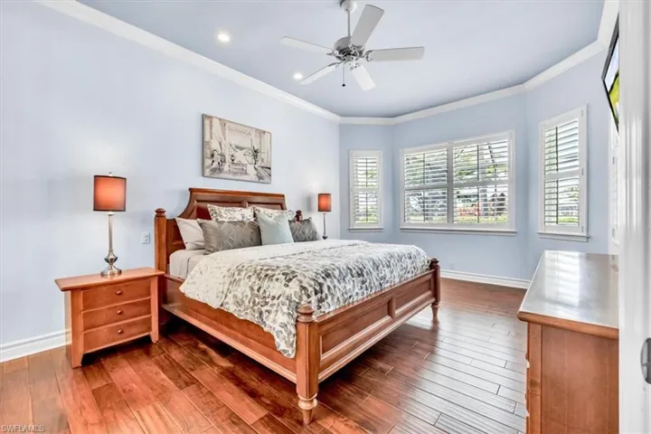 Hardwood flooring and crown molding in a room featuring bay windows with plantation shutters, recessed lighting, and a ceiling fan