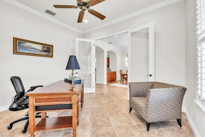 Spacious room with large tile flooring, crown molding, and a ceiling fan