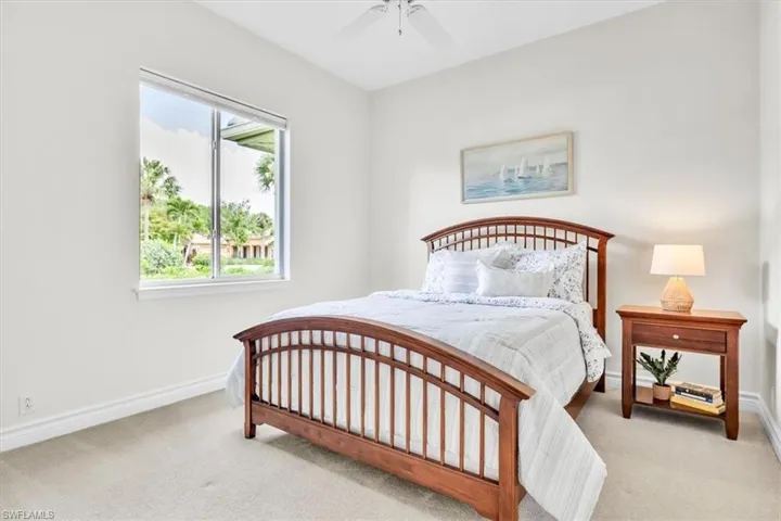 Bright bedroom featuring a large window, neutral wall paint, white trim, and light-colored carpeting
