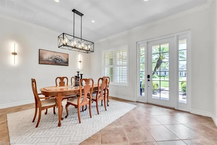 Spacious room featuring large format floor tiles, crown molding, and baseboards