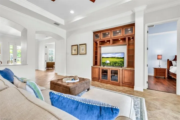 Spacious living area featuring a built-in entertainment center with integrated lighting and a stone countertop