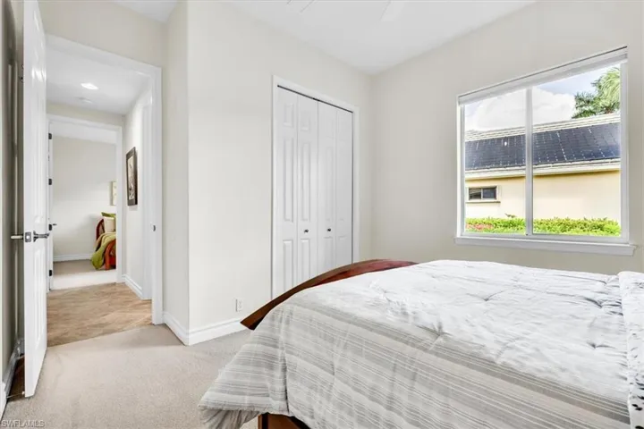 Bright interior space featuring carpet flooring, a window with exterior landscaping, white walls, and bi-fold closet doors