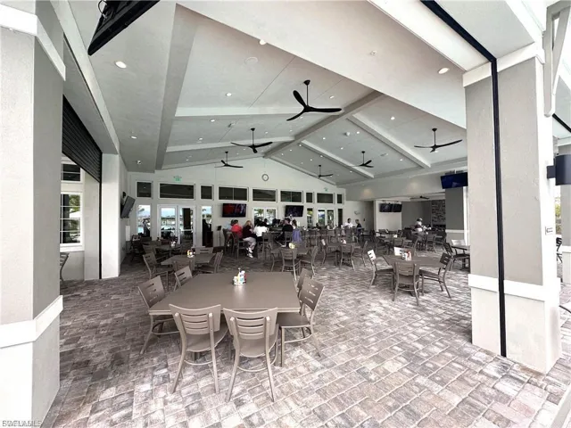 outdoor Dining space, Bar,  featuring a high ceiling, brick tiled floors, ceiling fans, and recessed lighting, and multiple TV's
