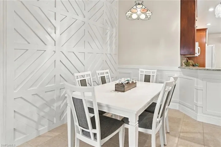 Decorative geometric wall paneling, tile flooring, wainscoting, and a stained glass pendant light fixture