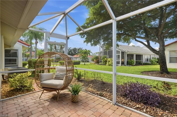 Screened patio with brick paver flooring, surrounded by landscaped garden beds, and a manicured lawn