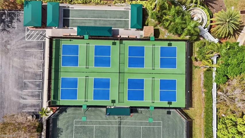 Four pickleball courts, two bocce ball courts, and a tennis court are present, complemented by a parking area and lush landscaping