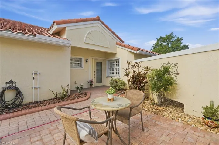 Tiled roofline, stucco exterior, paver patio, privacy wall, and mature landscaping