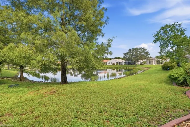 Expansive green lawn with mature trees and a tranquil pond