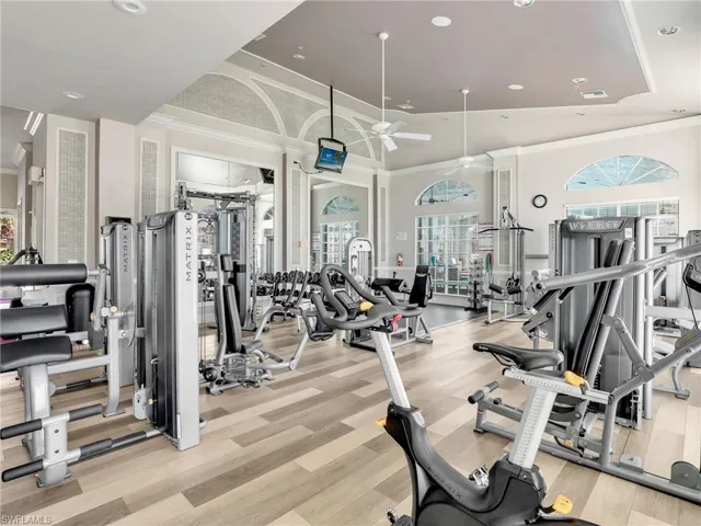 Fitness center with wood-finish flooring, vaulted ceilings, arched windows, and recessed lighting