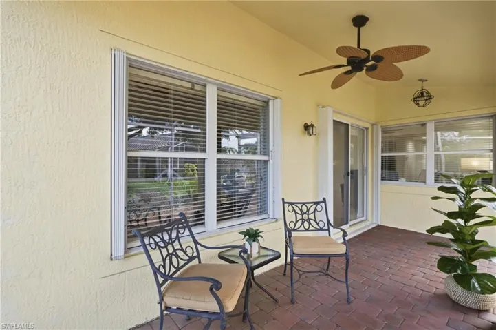 Covered patio featuring brick-finish flooring, a ceiling fan, and sliding glass doors