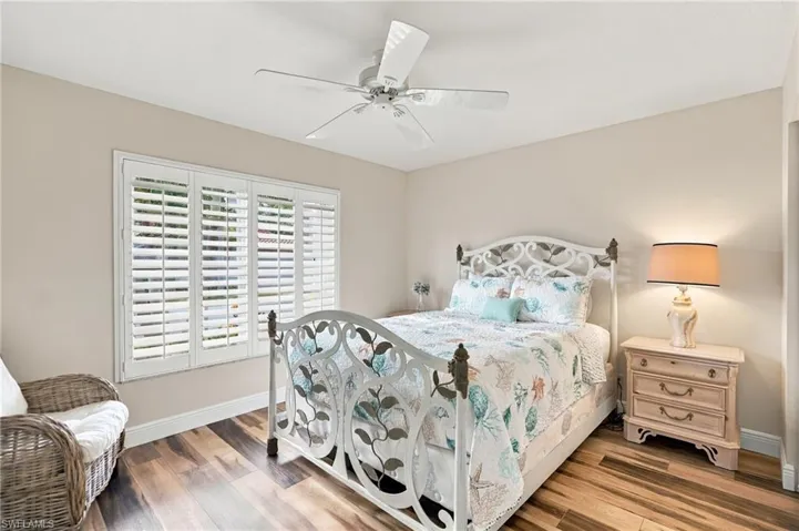 Wood-finish flooring, ceiling fan, white window shutters, and neutral wall tones