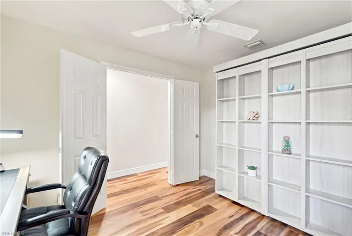 Wood-finish flooring, built-in shelving, ceiling fan, and white paneled doors