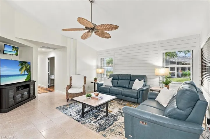 Vaulted ceilings, a decorative ceiling fan, and tile flooring