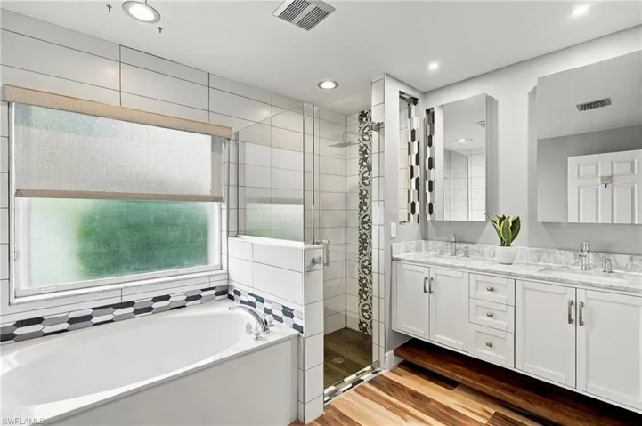 Dual vanity with white cabinetry, polished chrome fixtures, and stone countertops