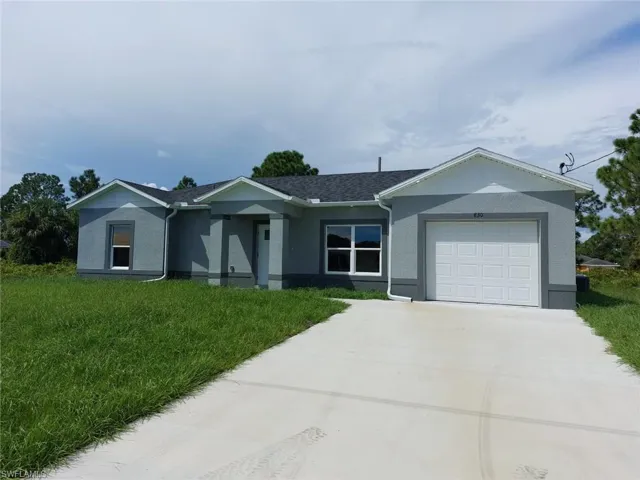 Single story home featuring a front yard, stucco siding, a garage, and driveway