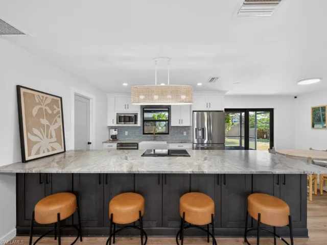 Kitchen with white cabinets, stainless steel appliances, backsplash, light wood-type flooring, and recessed lighting