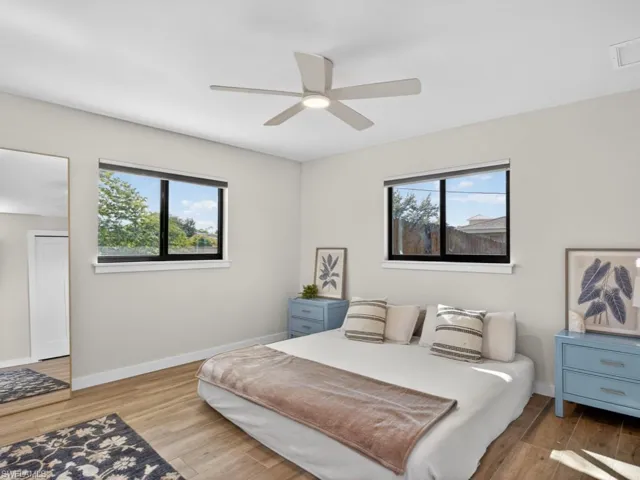 Bedroom with light wood-style floors, multiple windows, and a ceiling fan
