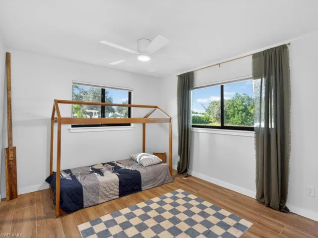 Bedroom with wood finished floors, a ceiling fan, and multiple windows