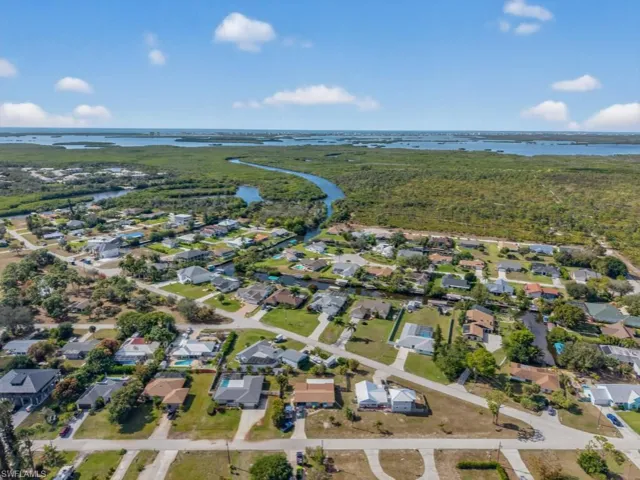 Aerial view of property and surrounding area featuring nearby suburban area and a nearby body of water