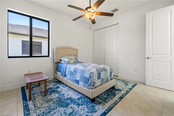 Tiled bedroom with ceiling fan and a closet