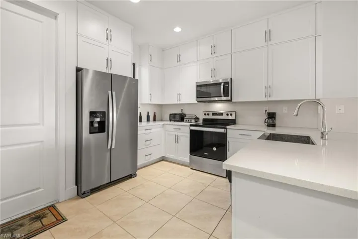 Kitchen featuring white cabinetry, sink, light tile patterned flooring, and stainless steel appliances